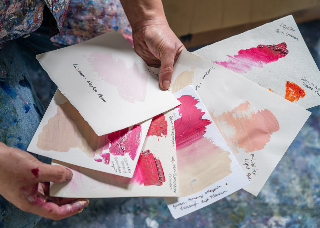 Victoria Wilson in her studio, showcasing various color studies of pinks, soft pinks, and oranges, exploring vibrant hues for her abstract artwork.