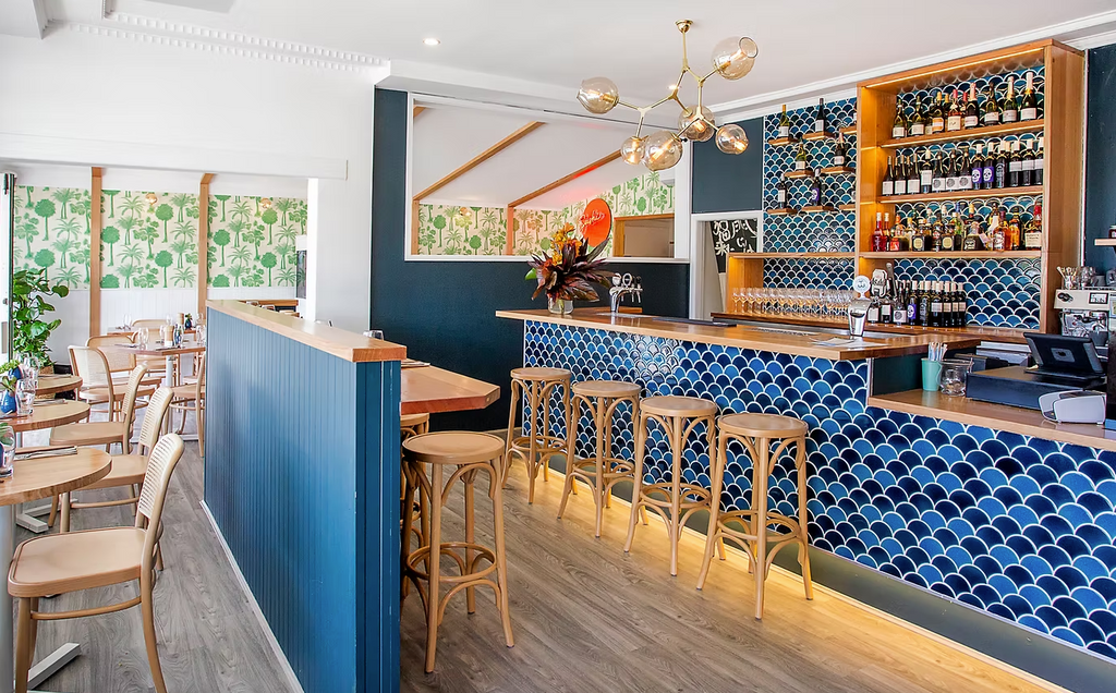 Modern bar with blue tiled wall and wooden stools
