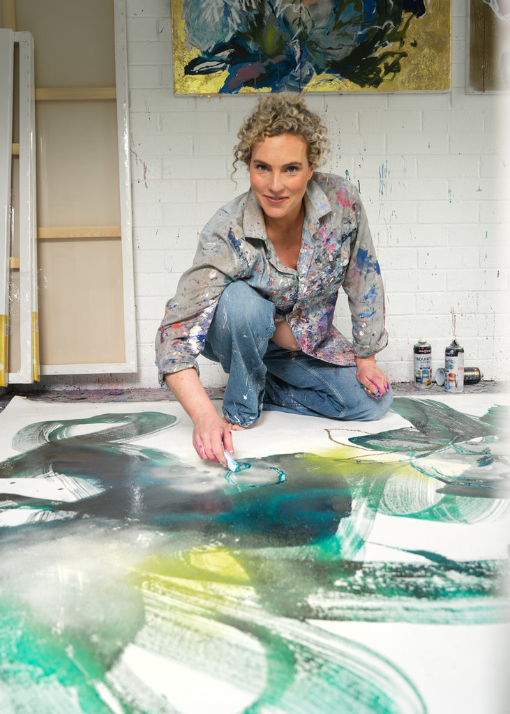 Victoria Wilson working with oil pastels on stretched canvas, creating a vibrant abstract floral artwork in her studio.