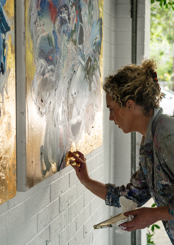 Victoria Wilson applying gold foil to her latest floral abstract artwork, showcasing her unique technique and artistic process.