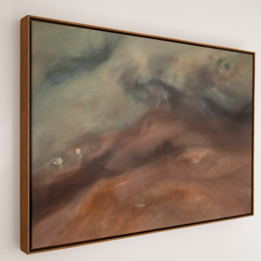 Framed abstract painting with brown and green tones on a white wall