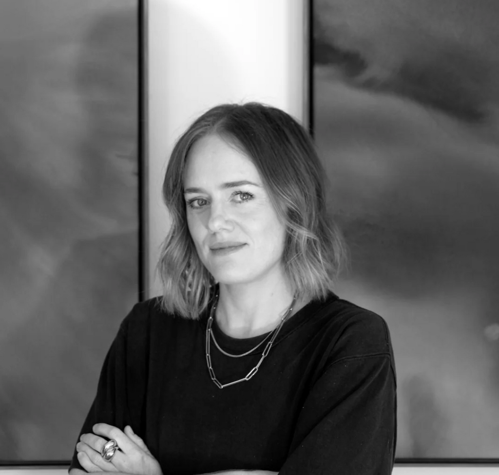 Black and white portrait of a woman with a blurred abstract painting in the background