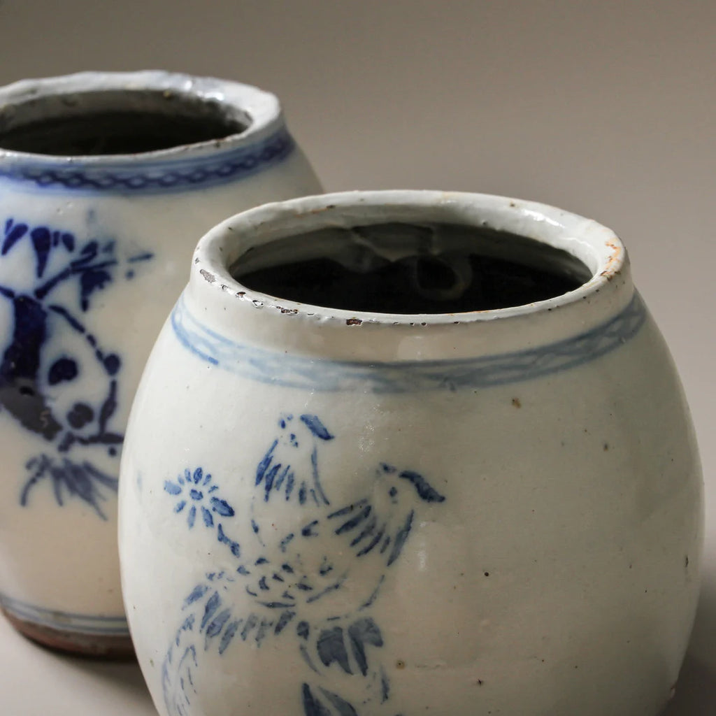 Two ceramic pots with blue floral designs on a neutral background