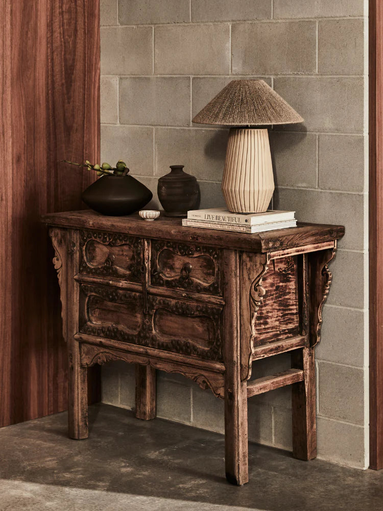 Wooden side table with decorative items against a tiled wall