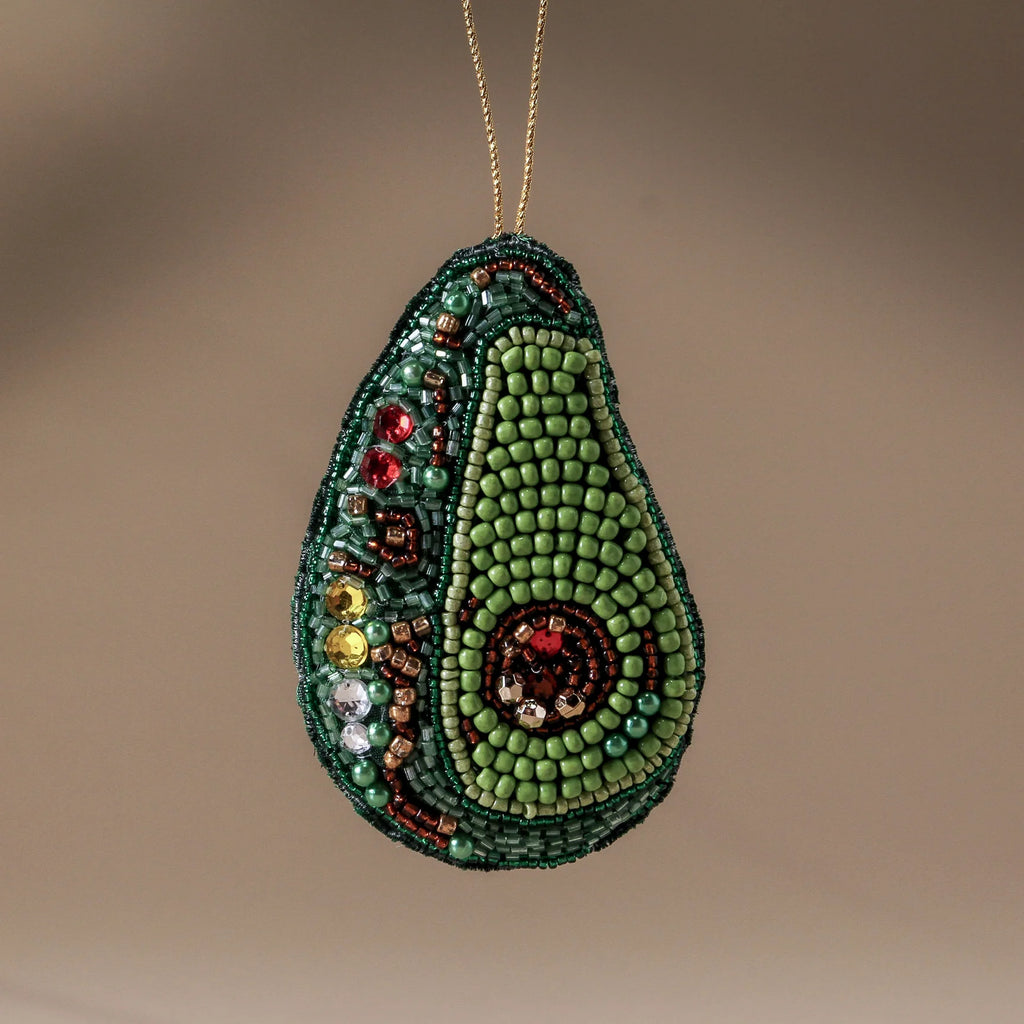 Beaded avocado ornament on a beige background