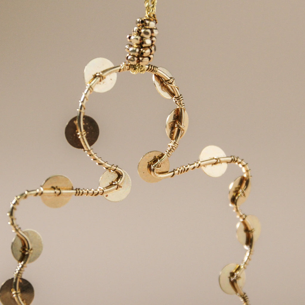 Gold Christmas decoration with circular and disc designs on a beige background