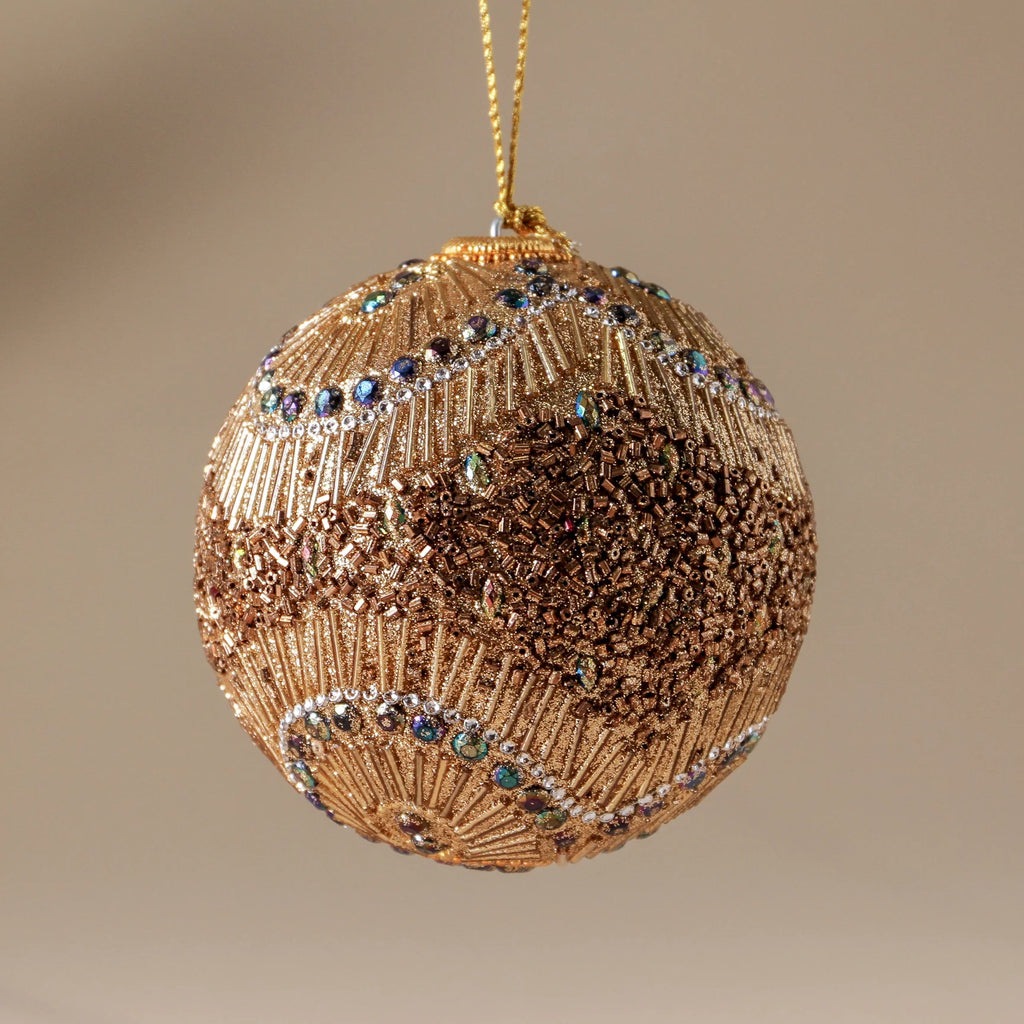 Decorative gold ornament with bead details on a beige background