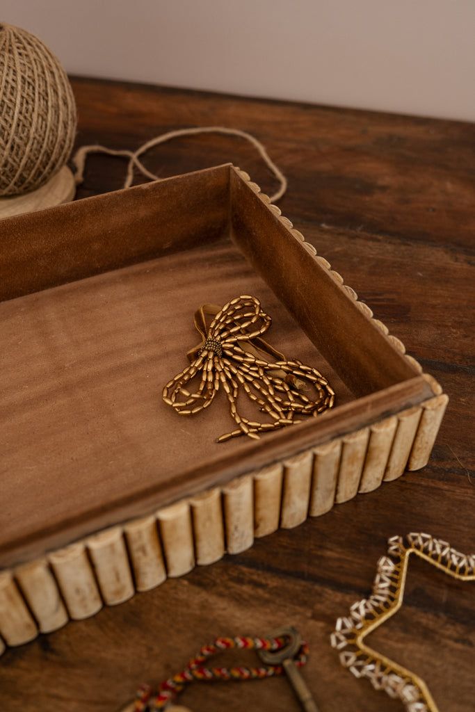Wooden tray with decorative gold bow on a wooden surface