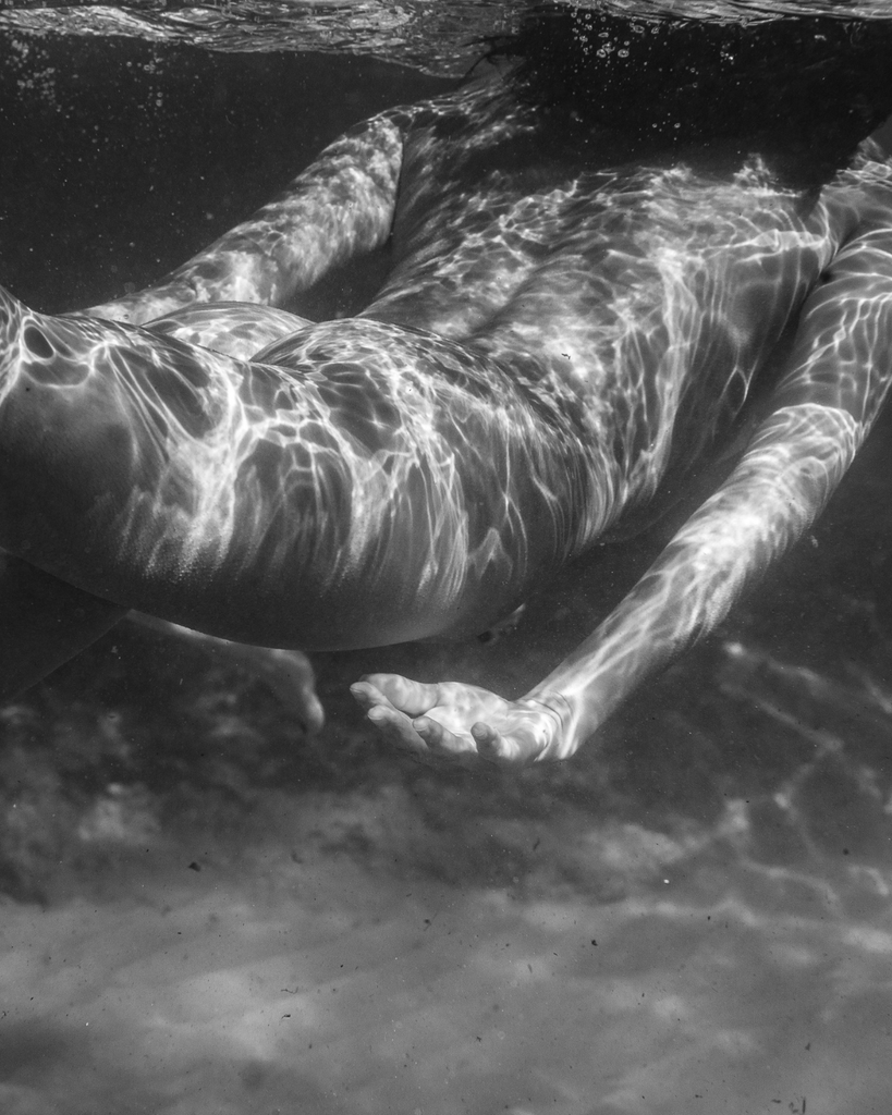Person underwater with sunlight filtering through the water