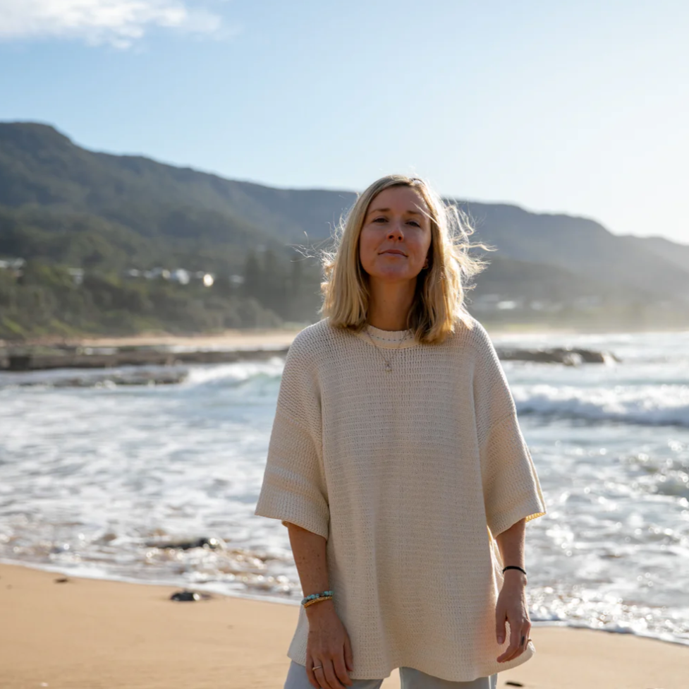 Woman standing on a beach with mountains in the background
