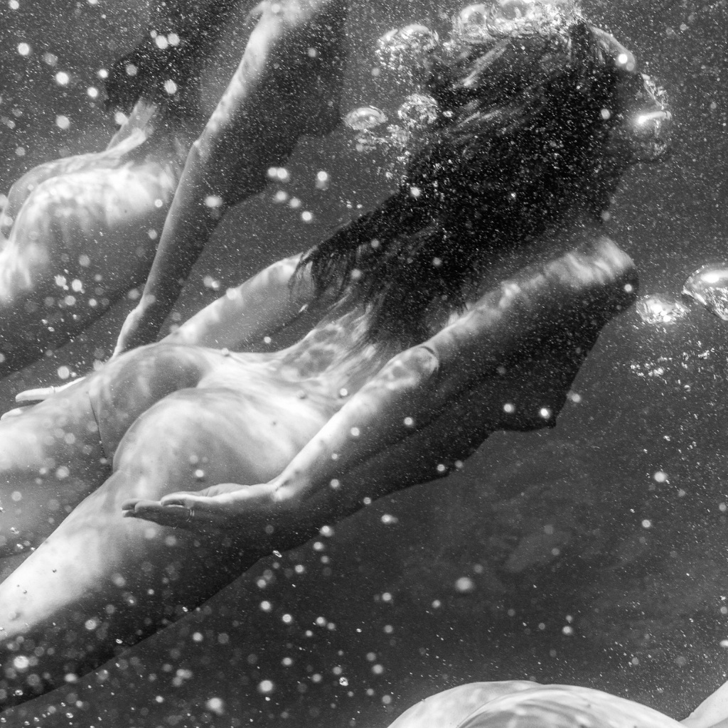 Black and white underwater scene with people swimming.