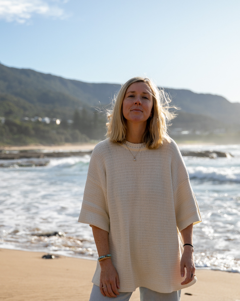 Woman standing on a beach with ocean and mountains in the background