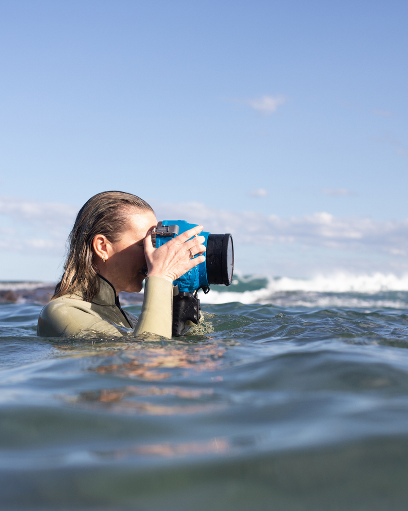 Person taking a photo with a large camera lens in the water