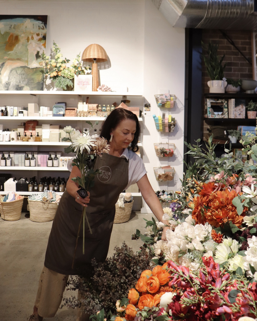 Woman in a floral shop holding a bouquet of flowers.