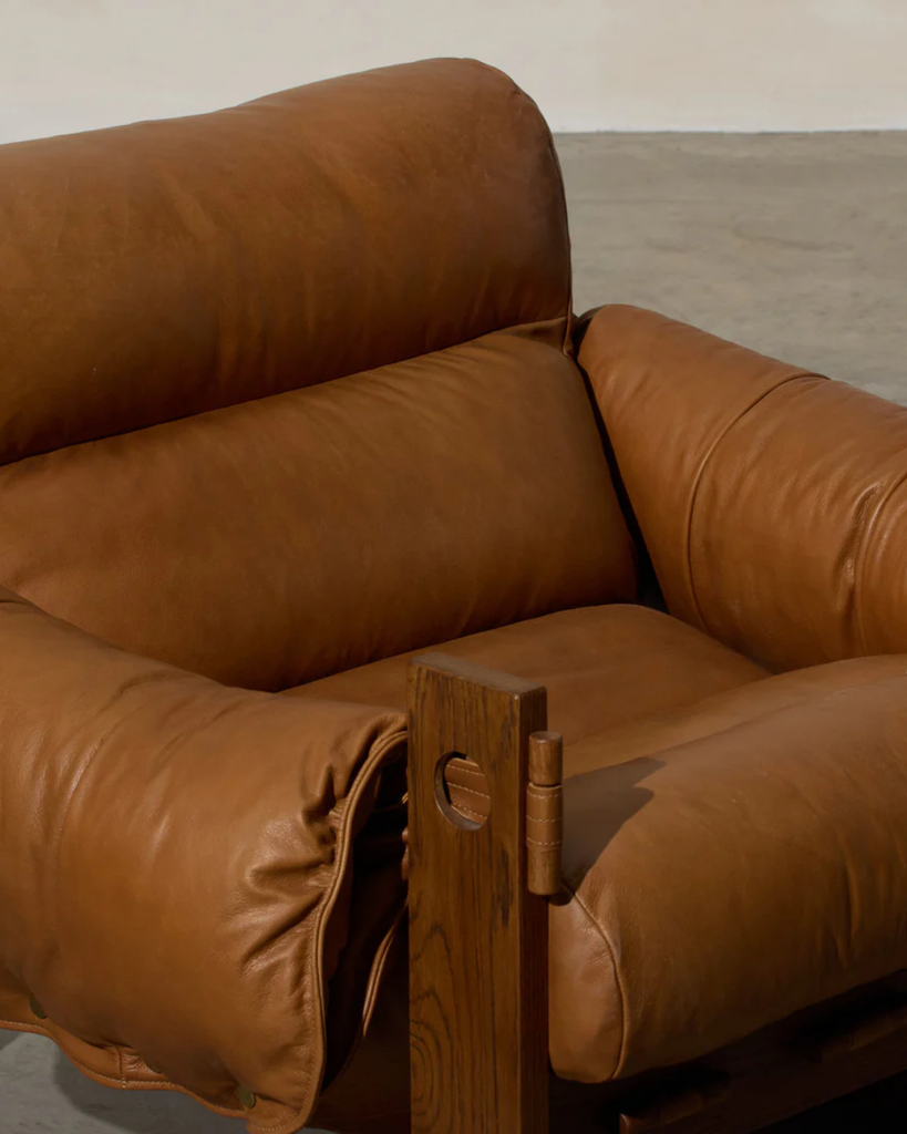 Brown leather sofa with wooden armrests on a neutral background