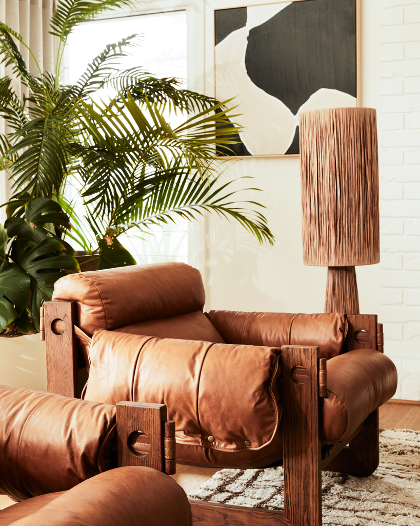 Brown leather armchair in a living room with a plant and abstract art on the wall.