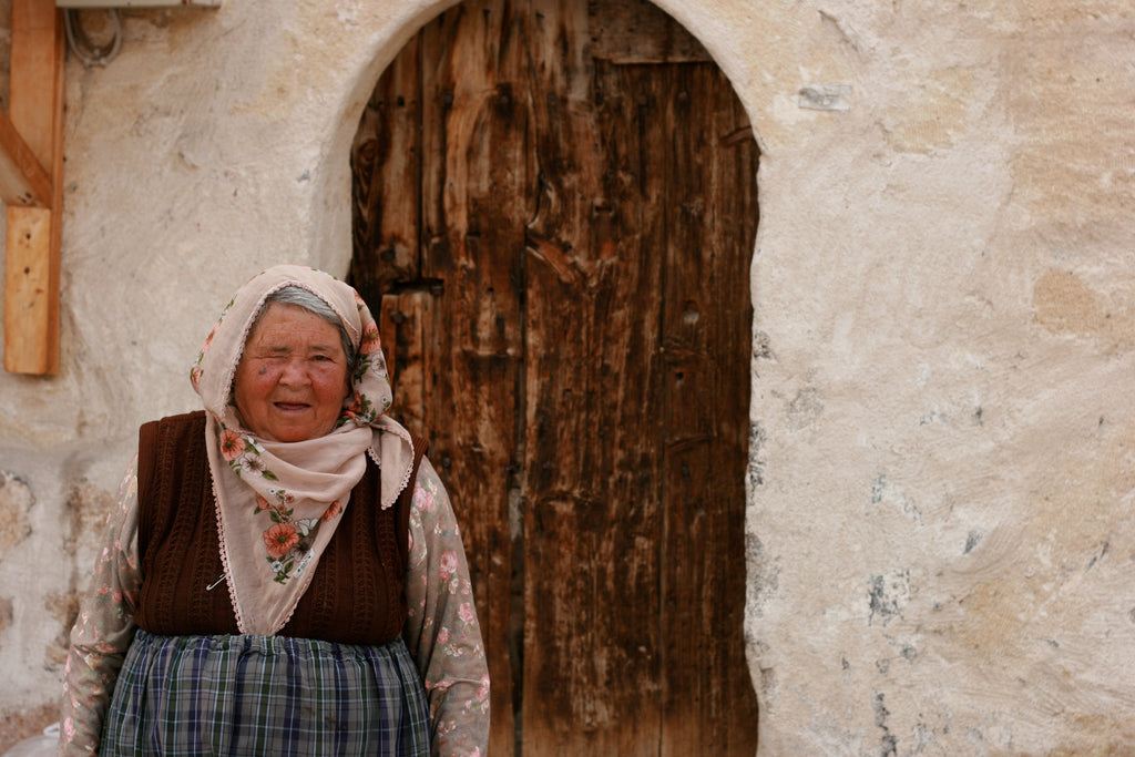 Woman in traditional attire standing in front of a rustic wooden door.