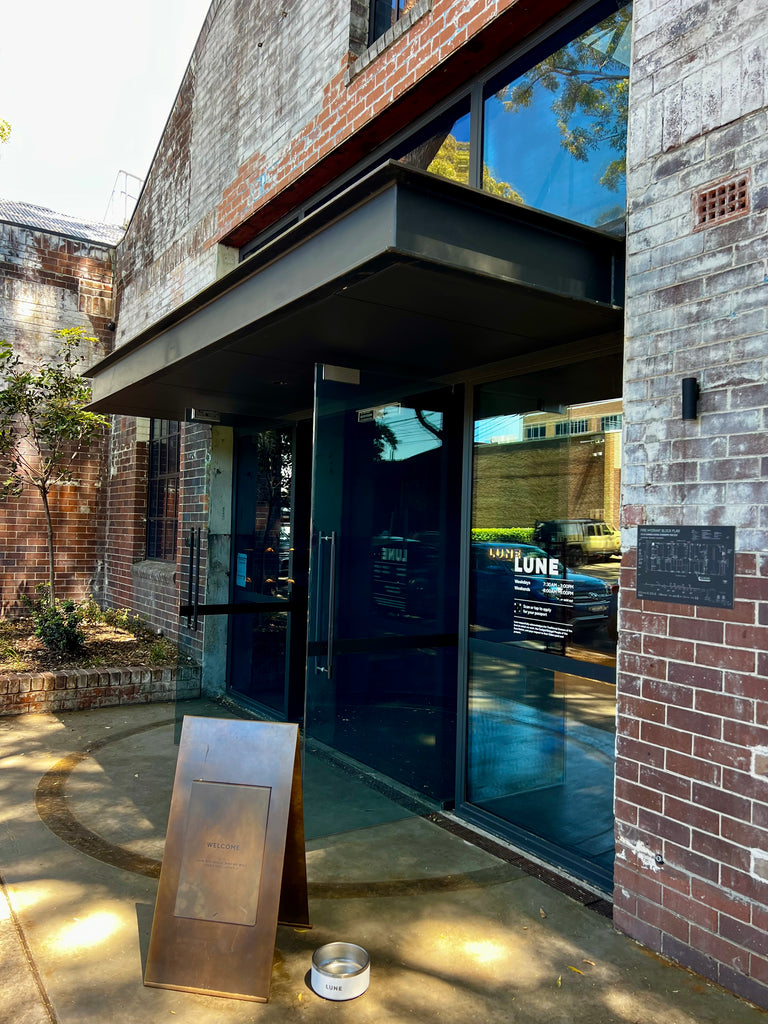 Modern building entrance with glass doors and a metal sign on a concrete pavement.