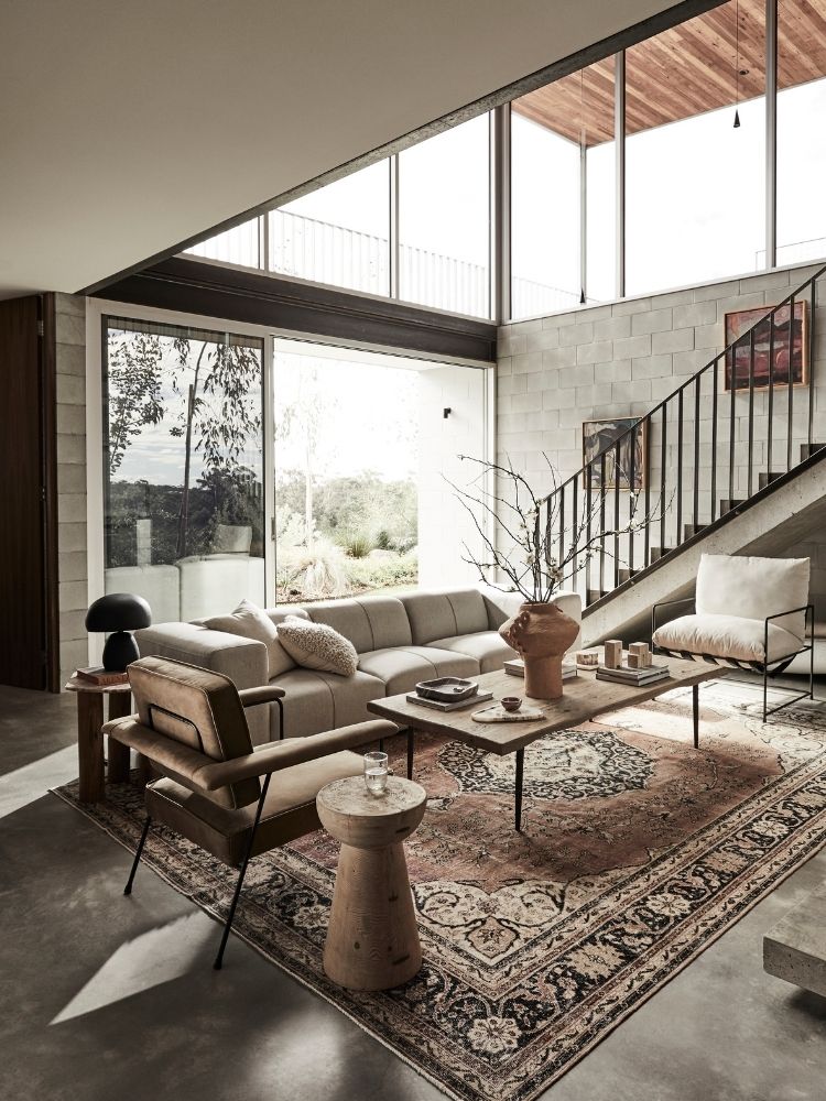 Modern living room with large windows, gray sofa, and decorative Turkish Rug rug.