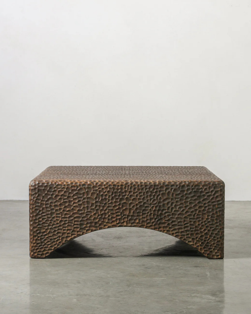 Textured brown bench on a gray floor with a white wall background