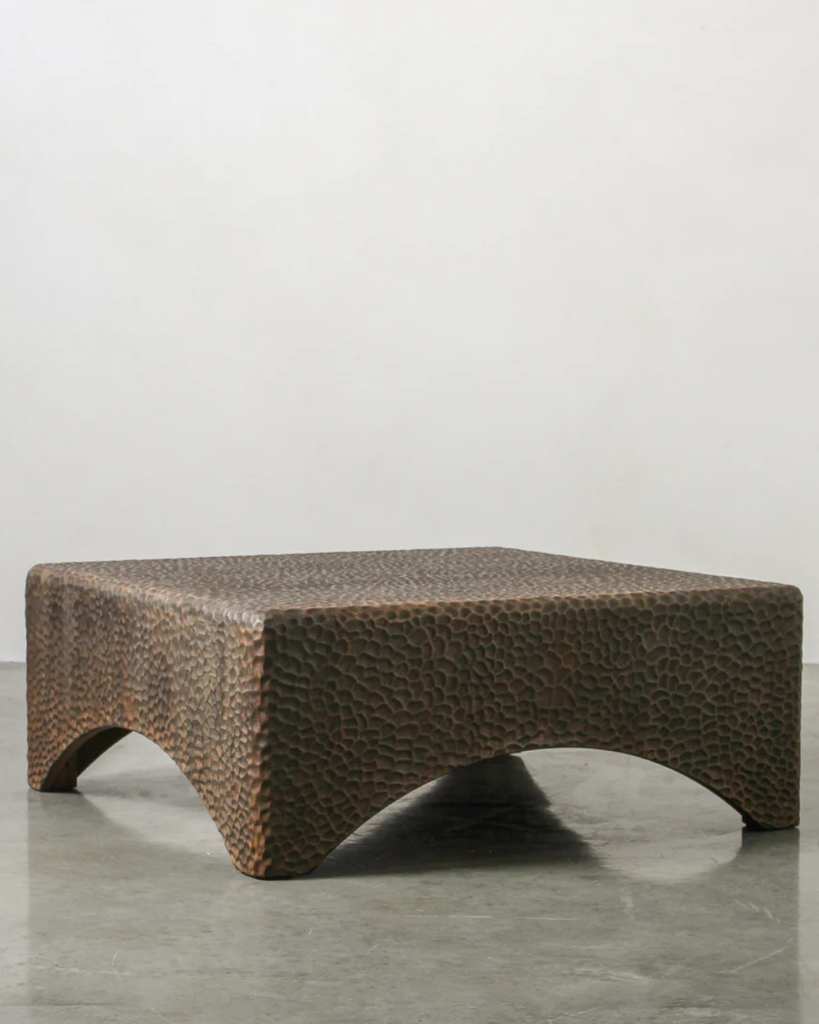 Textured square coffee table on a gray surface with a light gray background
