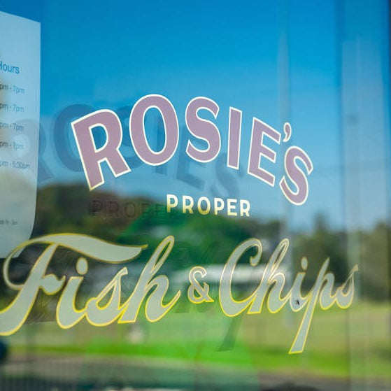 Window sign for Rosie's Proper Fish & Chips with outdoor view