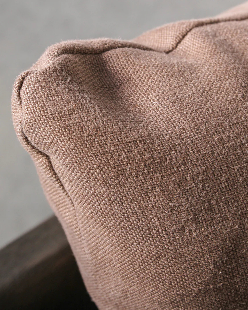 Close-up of a textured brown cushion on a neutral background