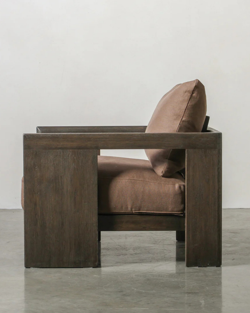 Brown leather armchair with wooden frame on a gray floor and white wall background