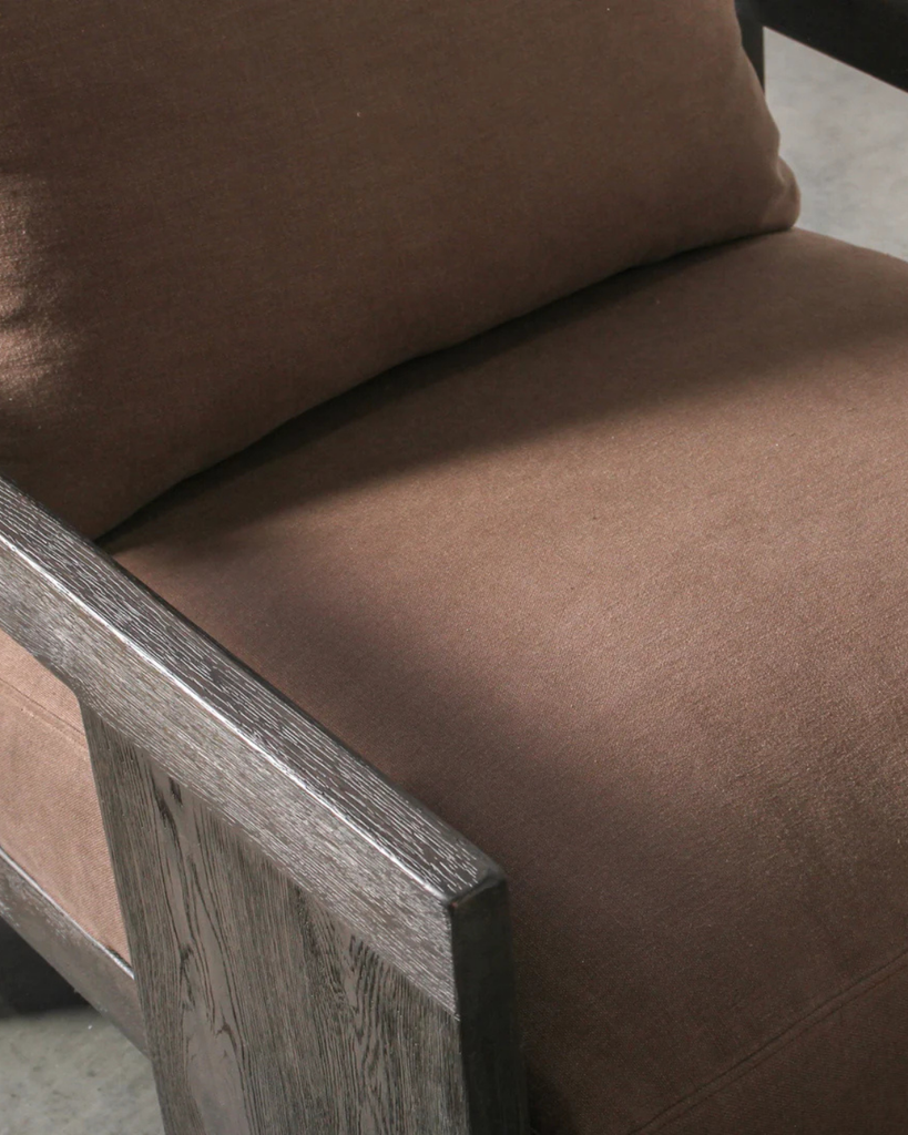 Brown cushioned chair with wooden armrest