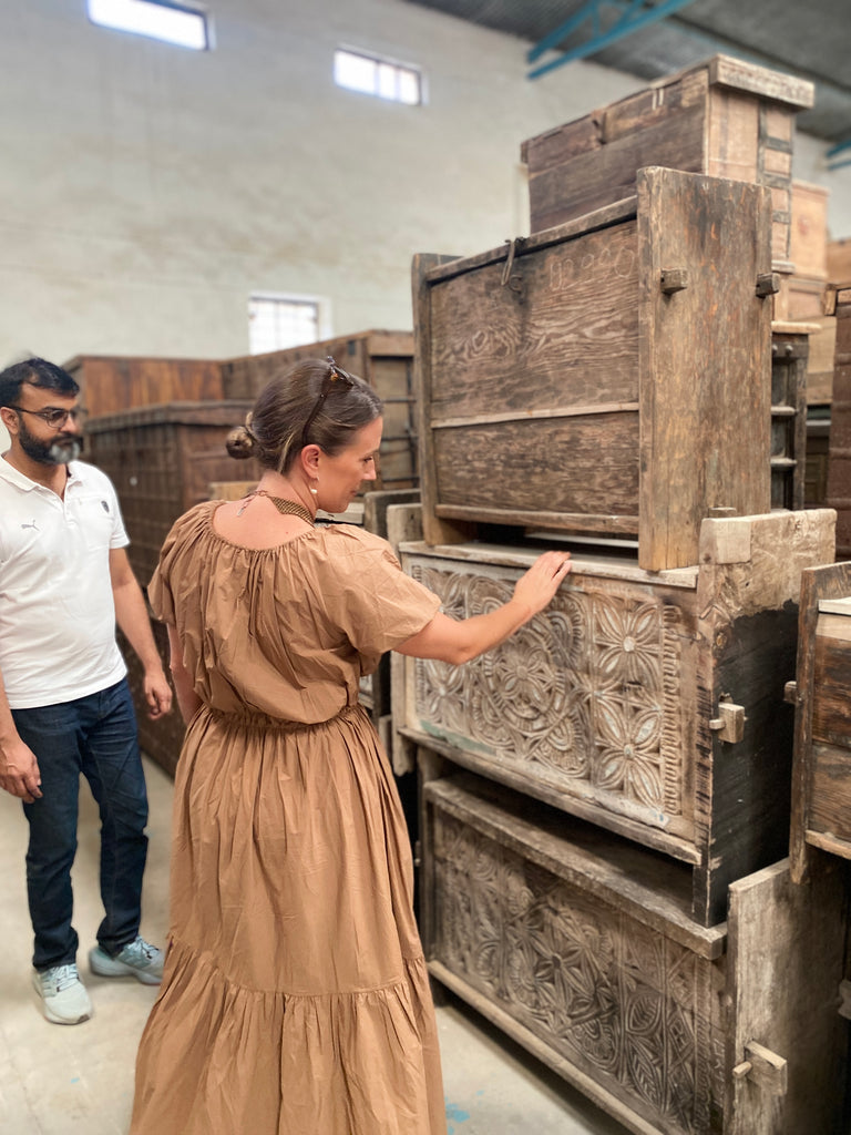 Two people examining wooden furniture in a warehouse setting