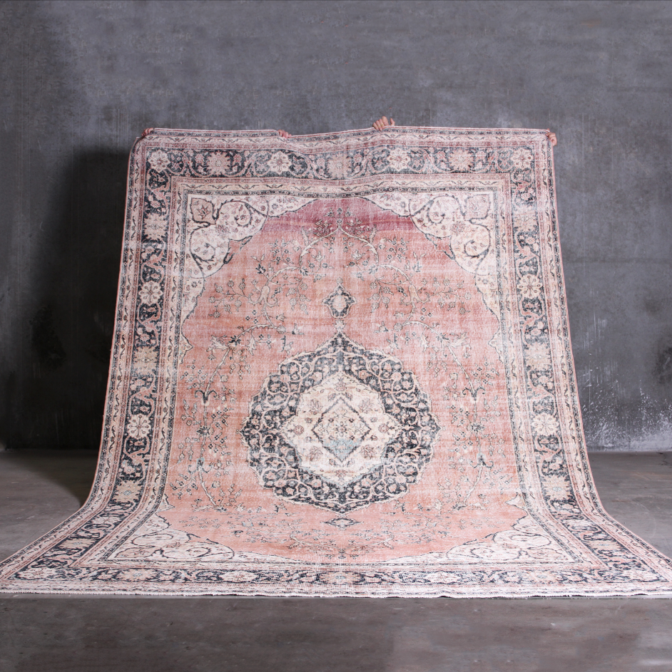 Vintage pink and beige patterned rug on a dark gray background