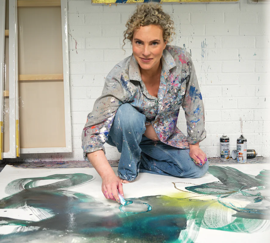Artist working on a large abstract painting in a studio.