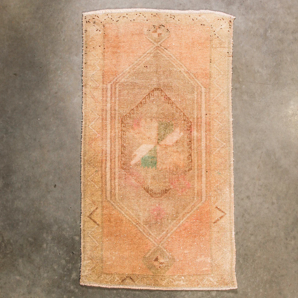 Vintage-style rug with geometric pattern on a textured gray background